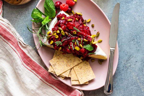 Friends-giving cranberry and pistachio cheese with crackers on a pink plate.