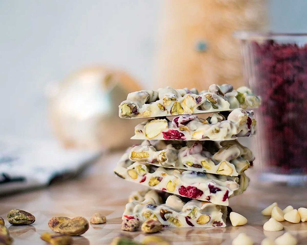 A stack of festive Christmas bark on a table, made with white chocolate and pistachios.