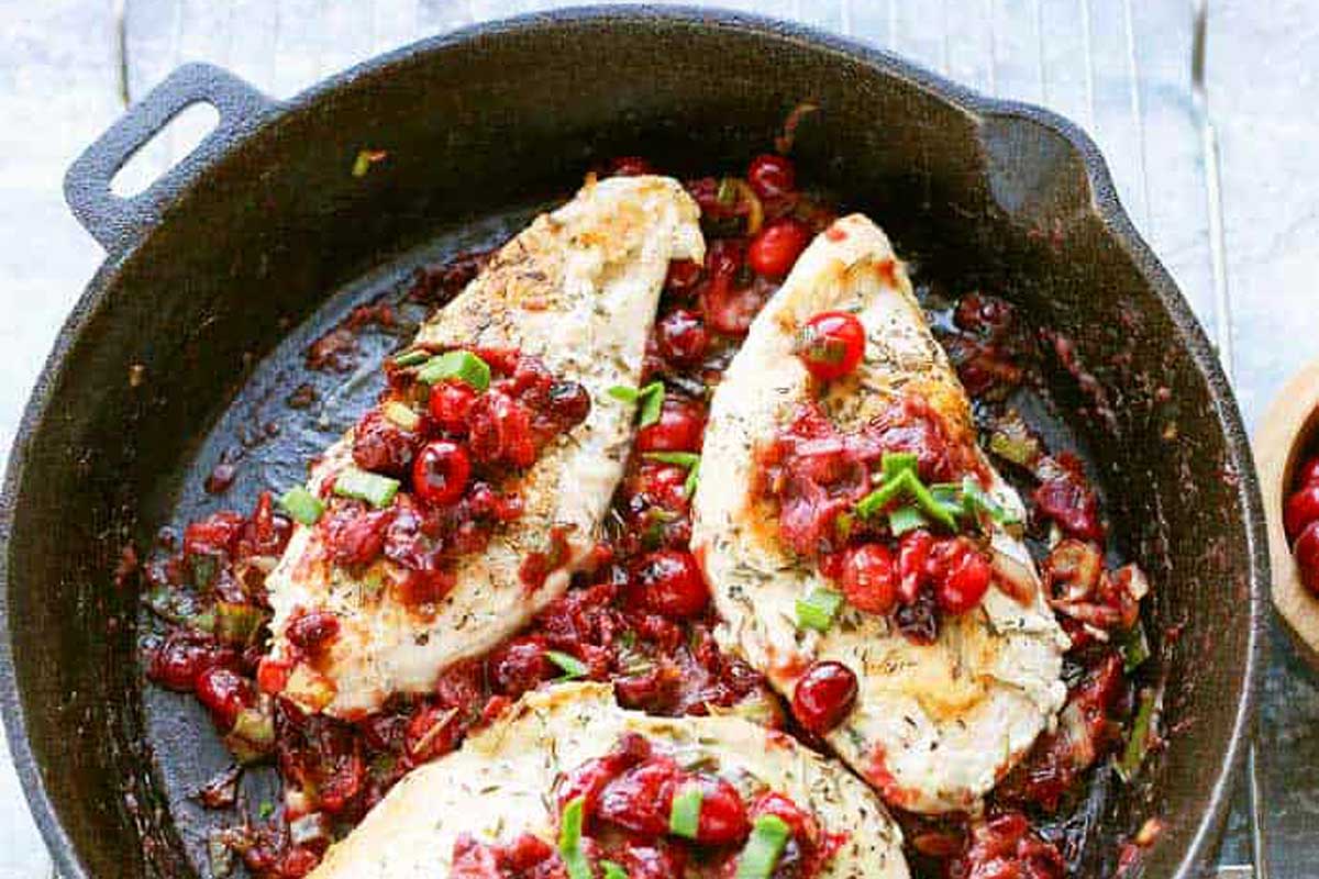 Chicken with cranberry sauce in a skillet.