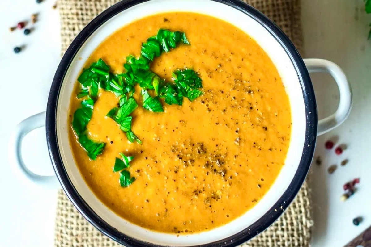A comforting winter dinner featuring a delicious bowl of carrot soup garnished with fresh parsley.