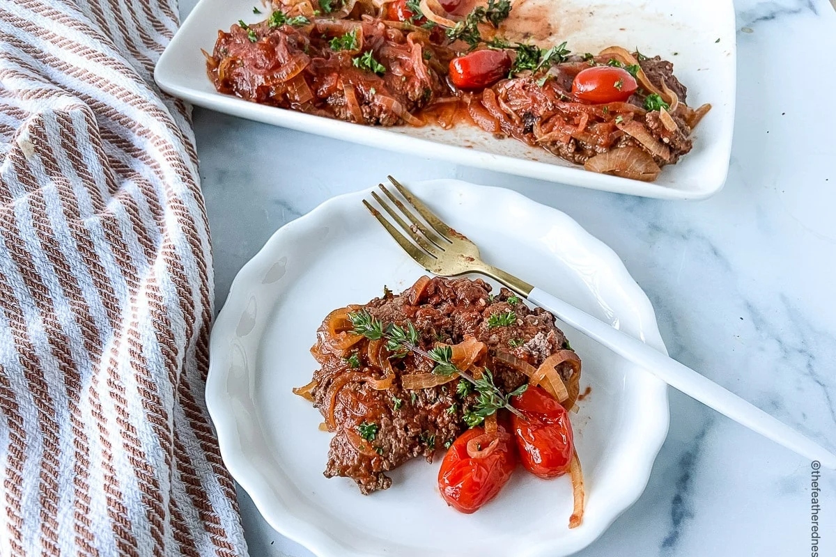Two comforting dinners with meat and tomatoes on plates.