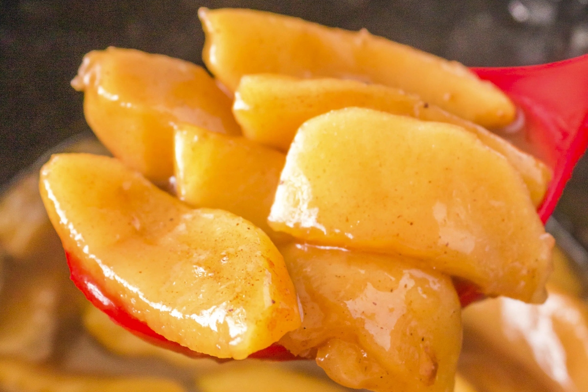 94 Spot-On Copycat Recipes You'll Regret Not Trying Sooner 41 A red spoon full of caramelized apples.
