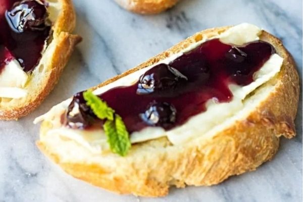 Two slices of bread with blueberry jam and mint, perfect for a refreshing snack or light breakfast.