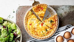 A person expertly cutting a mouthwatering quiche, showcasing their culinary expertise in creating unique and tantalizing recipes.