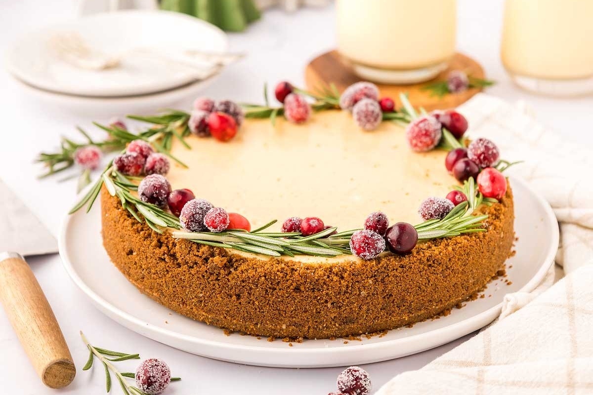 A cranberry cheesecake with sprigs of rosemary on a white plate.