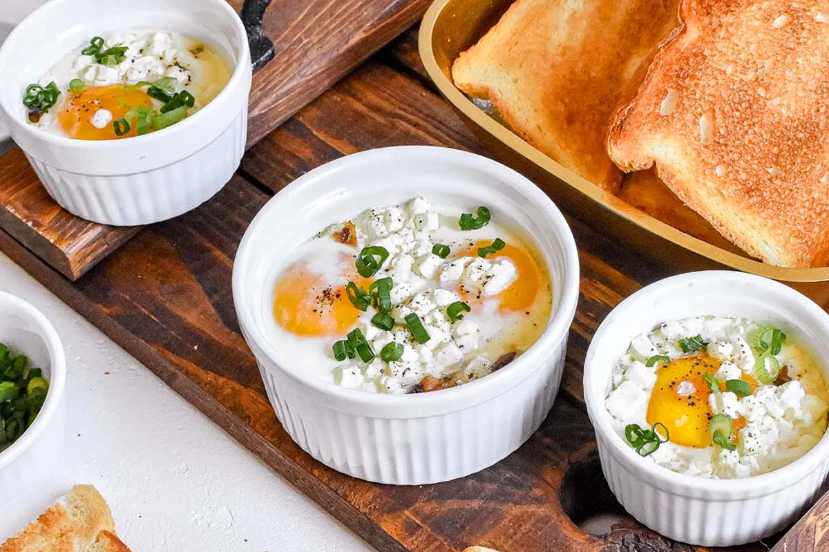 Three bowls with eggs and bread on a table.