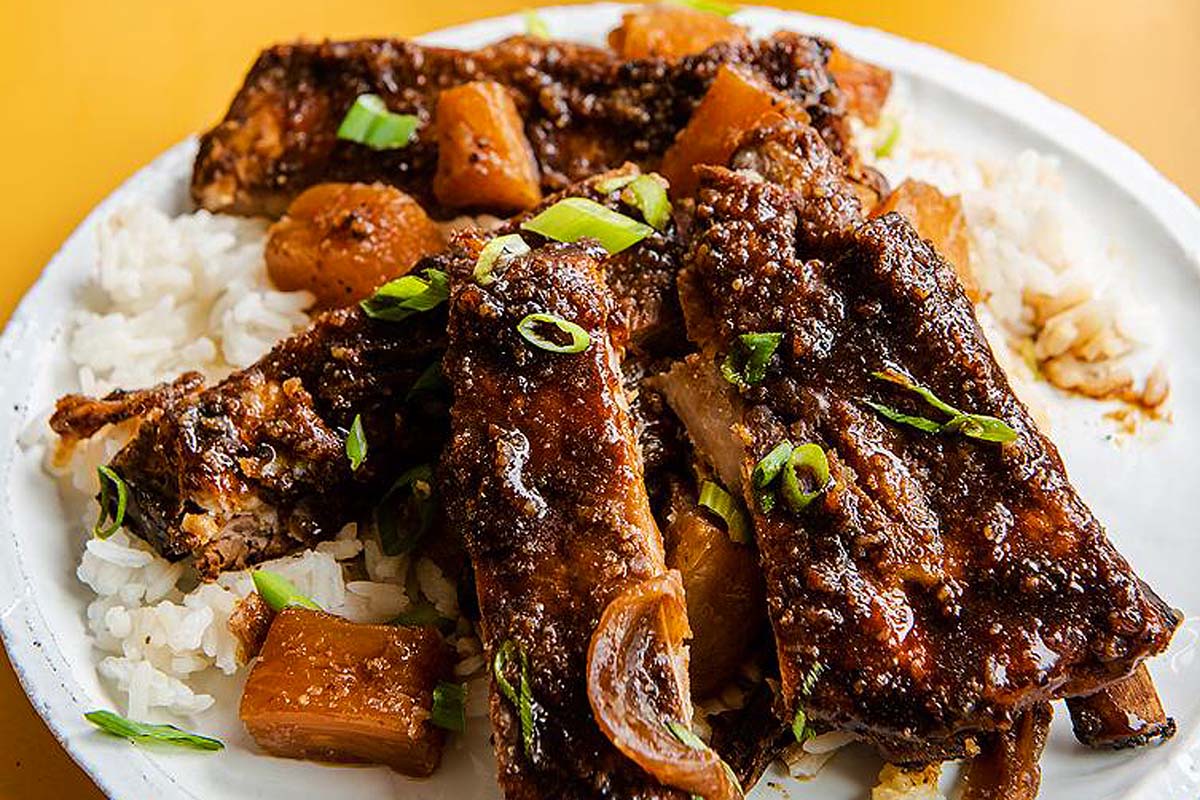 Ribs on a plate with rice and onions.