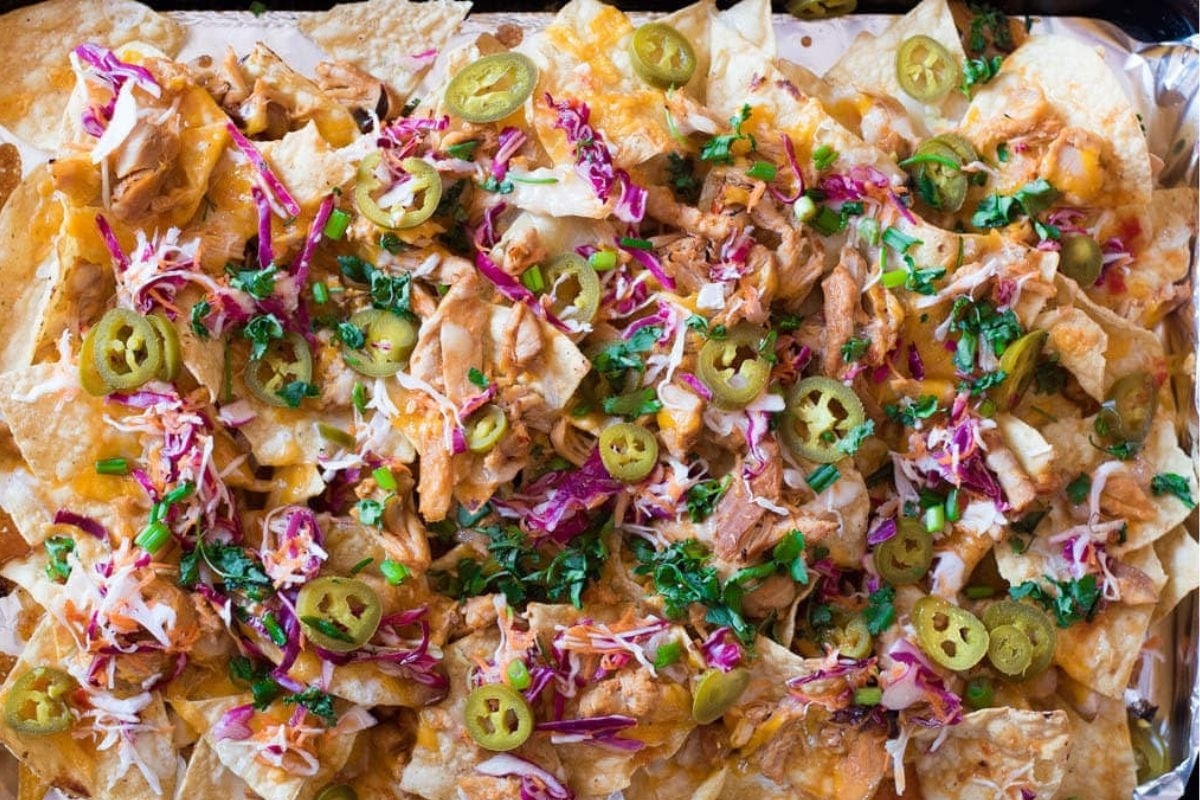 A tray of nachos with a variety of toppings.