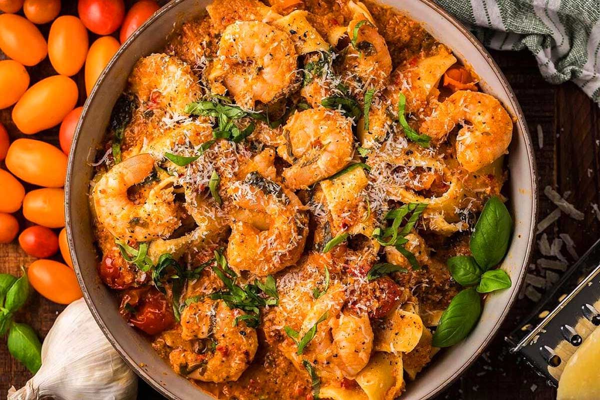 A delicious pasta dish featuring succulent shrimp and ripe tomatoes, showcased on a rustic wooden table.