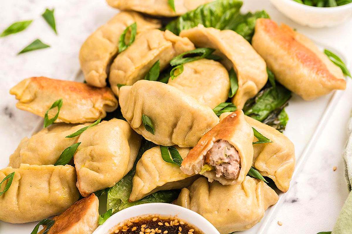 Dumplings on a white plate with dipping sauce. This is one of the best Asian recipes.