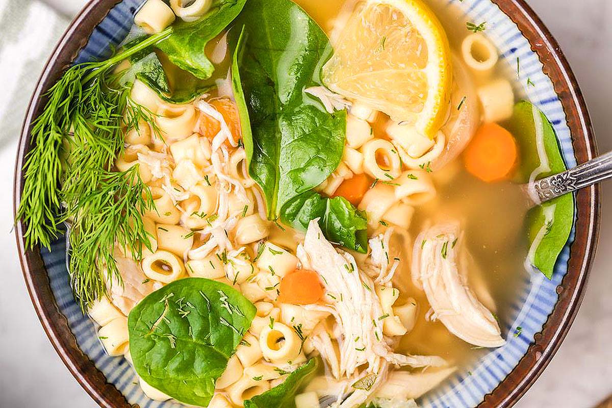A slow cooker soup filled with chicken noodle, spinach, and lemon.