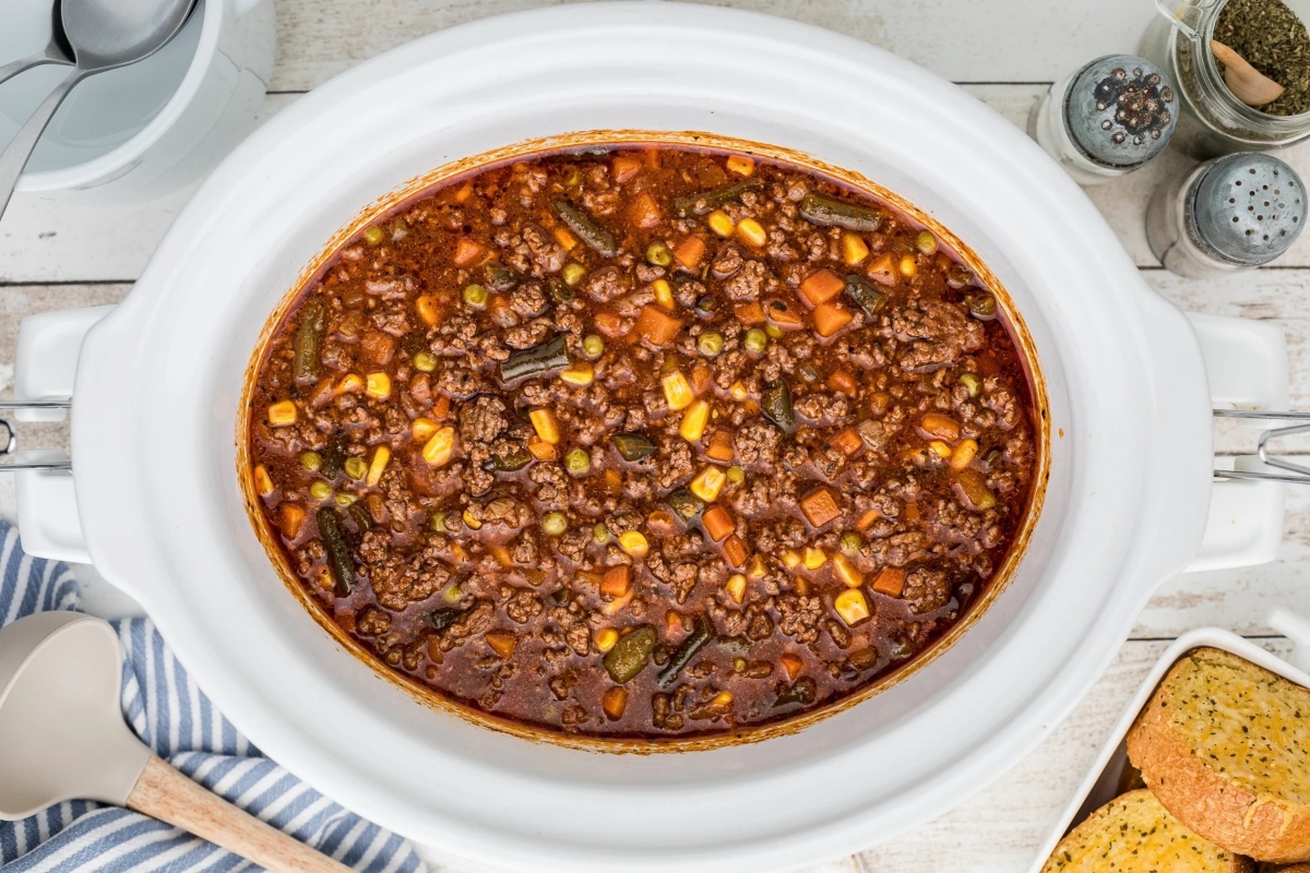 A crock pot full of chili and cornbread packed with frozen mixed vegetables.