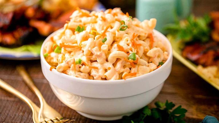 Macaroni and cheese in a bowl on a wooden table resembling a pasta salad.