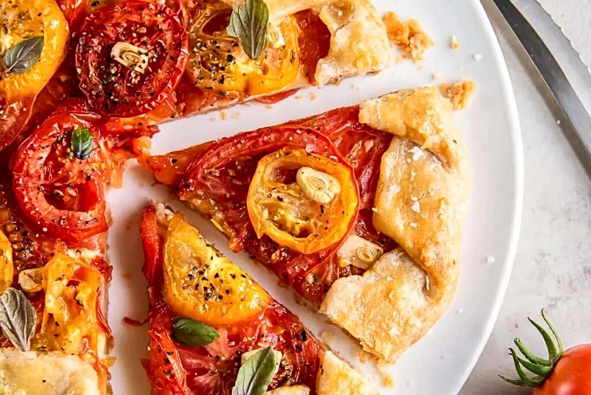 A tomato-based pizza topped with a flavorful blend of herbs, served on a pristine white plate.