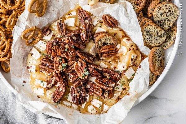 A bowl of pecan brie cheese with crackers and pretzels, perfect for a delicious Brie recipe.