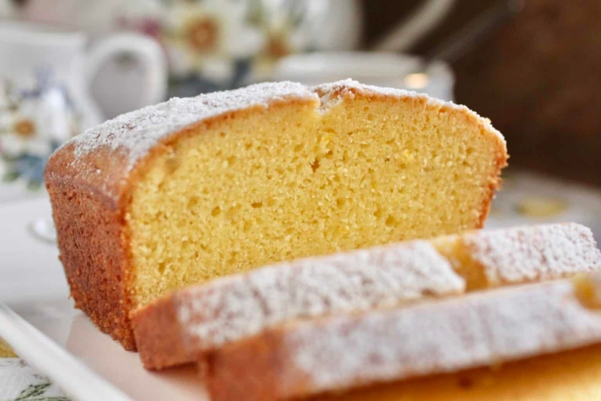 A slice of lemon pound cake on a white plate, perfect for holiday gatherings or enjoying alongside a hot beverage from Starbucks.