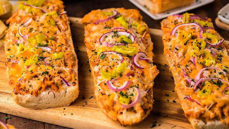 Three slices of bread with onions and cheese on a cutting board.