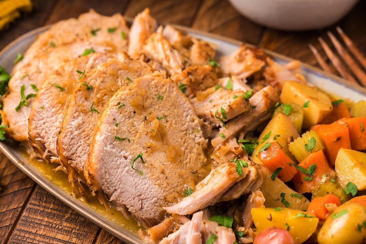 A hearty winter dinner featuring succulent pork tenderloin served on a plate alongside savory potatoes and carrots – the ultimate comfort food.