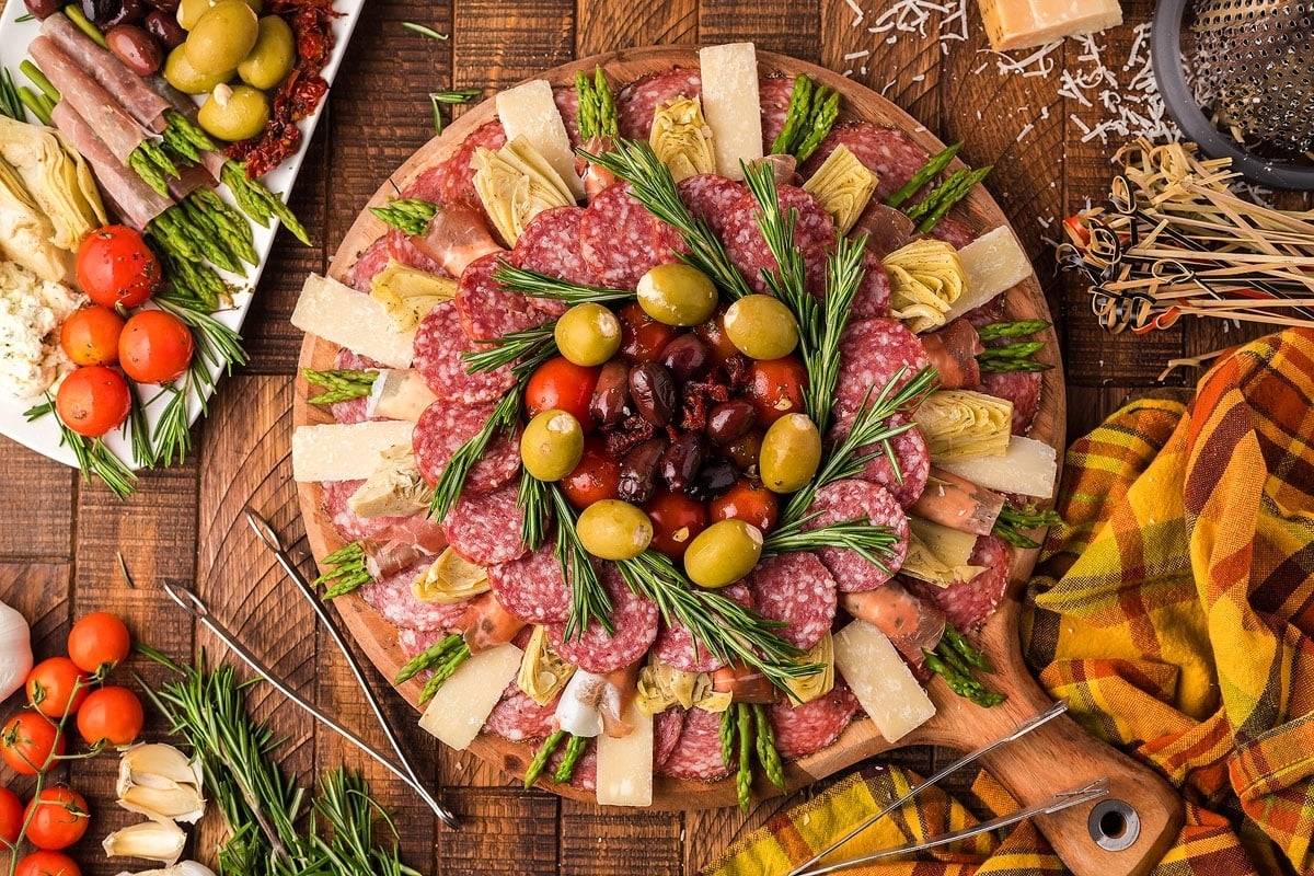 A festive Christmas charcuterie platter of meats and vegetables elegantly displayed on a rustic wooden table.