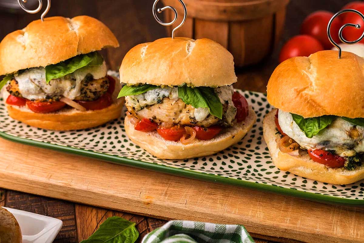 Three chicken sliders with tomatoes and basil on a Pesto Recipes plate.