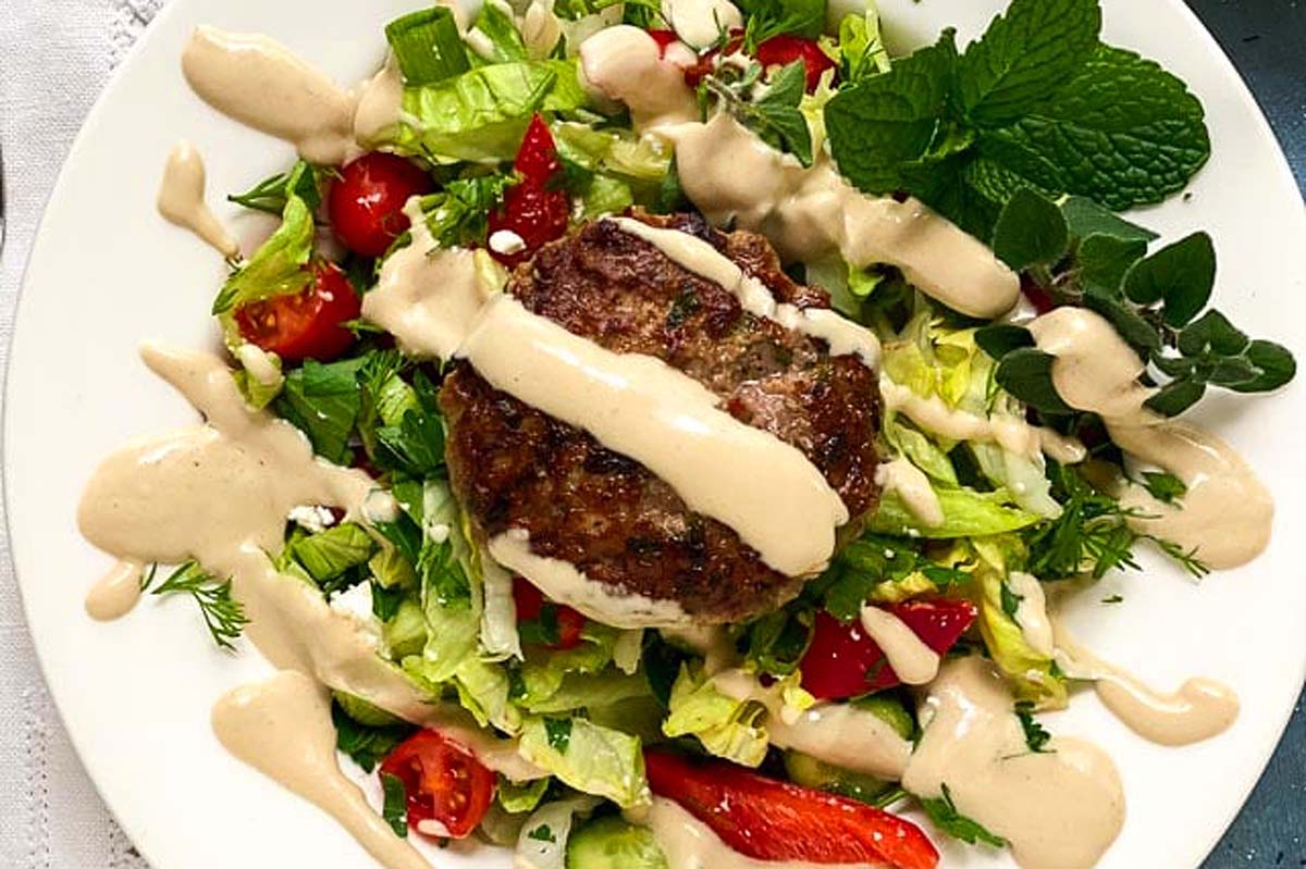 A plate with a salad and a burger on it.