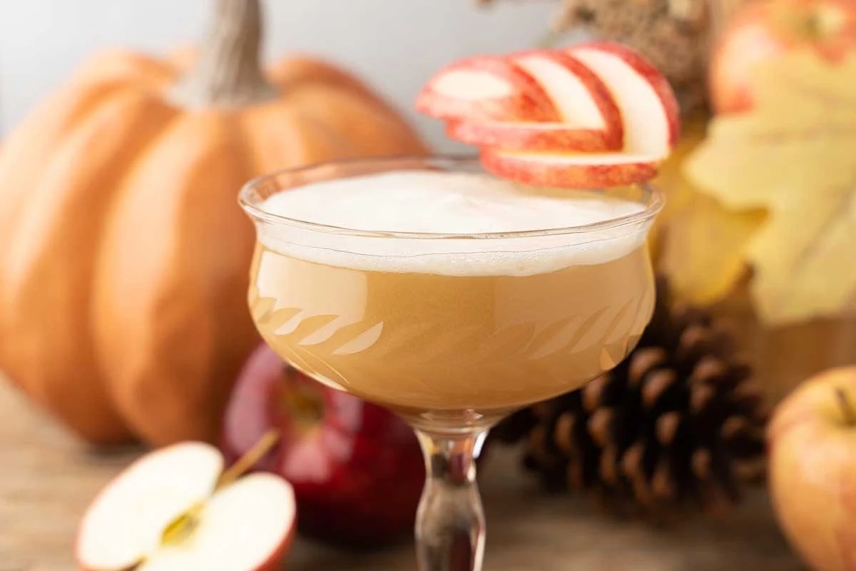 Maple apple whiskey sour cocktail glass with apple on the rim. This is one of the best Thanksgiving cocktail recipes.