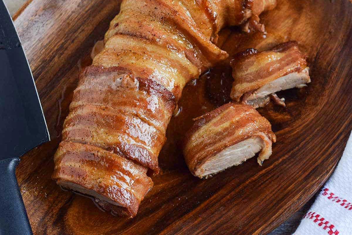 Bacon wrapped in bacon on a wooden cutting board.