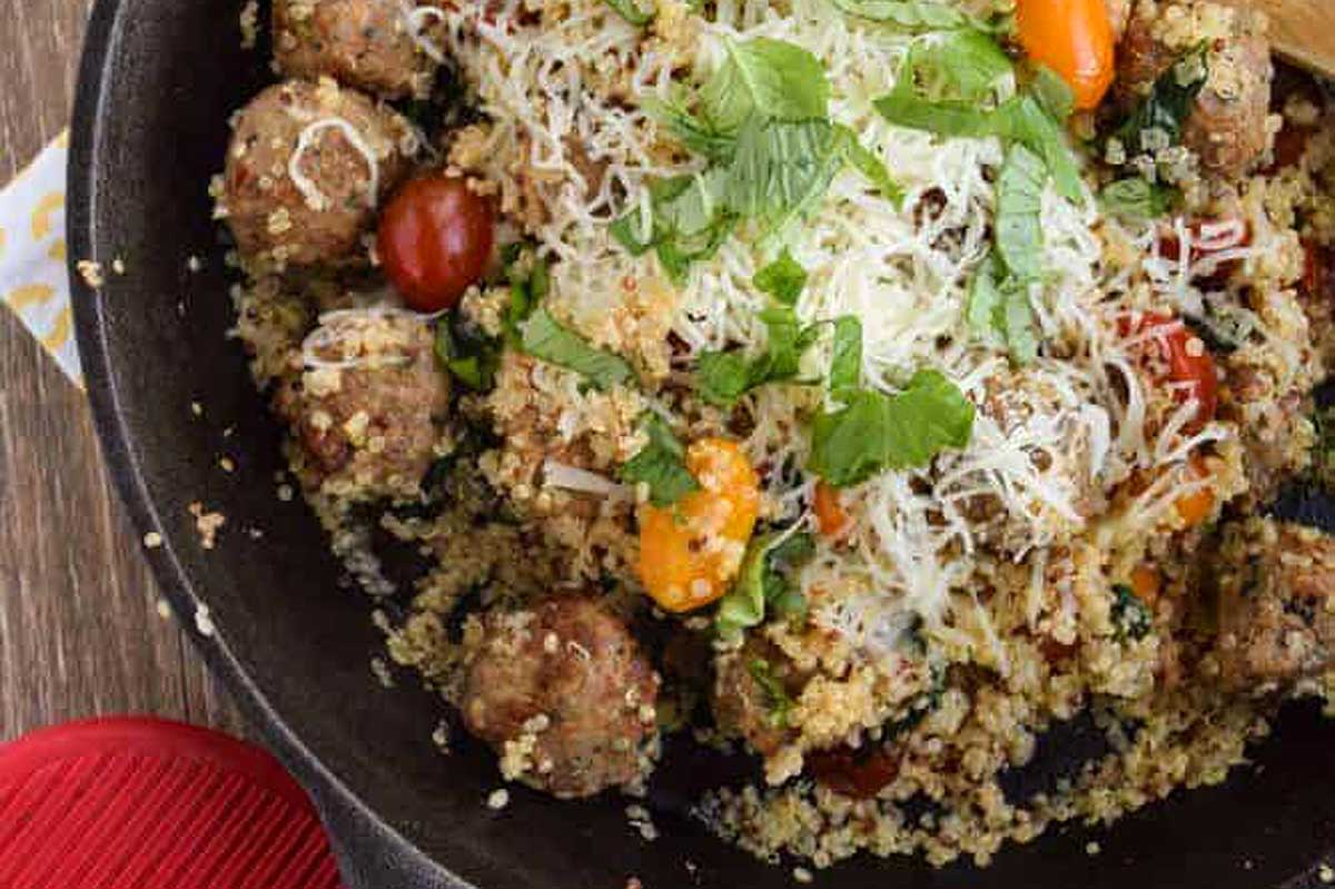 A skillet filled with meatballs and tomatoes.
