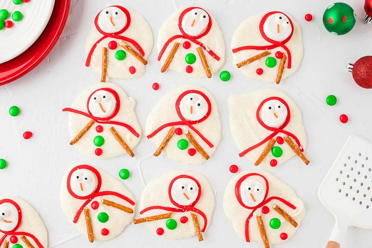 Christmas-themed snowman cookies decorated with sprinkles and candy are beautifully arranged on a plate.