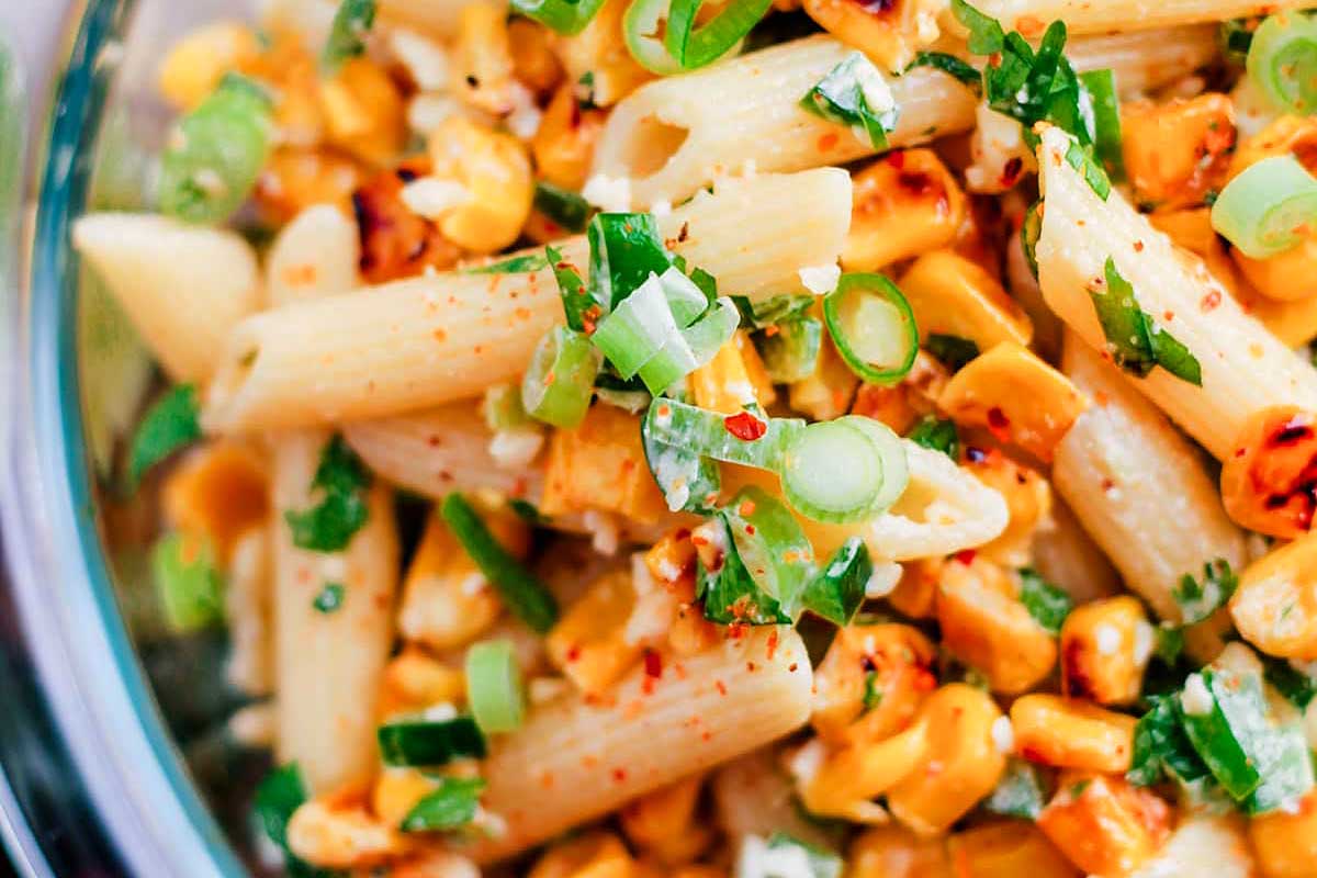 A pasta salad with grilled corn and green onions.