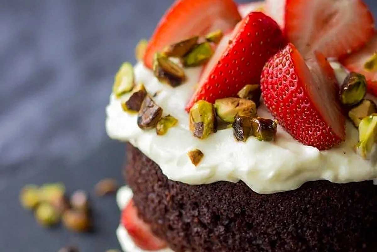 A chocolate cake topped with strawberries and pistachios. This decadent dessert recipe combines the rich flavors of chocolate and the irresistible crunch of pistachios, creating a delightful treat that is perfect