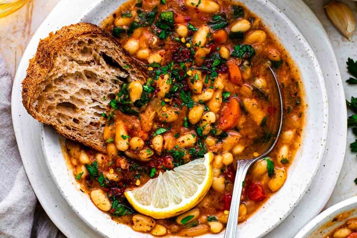 A comforting bowl of white bean soup, perfect for the winter season. Served with a side of warm bread.
