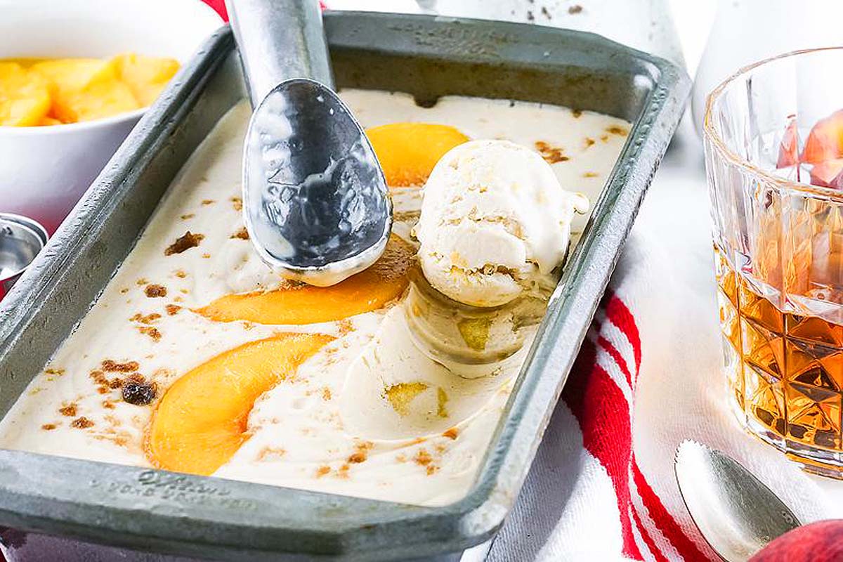 Peach ice cream in a pan with a spoon, sprinkled with cinnamon for added flavor.