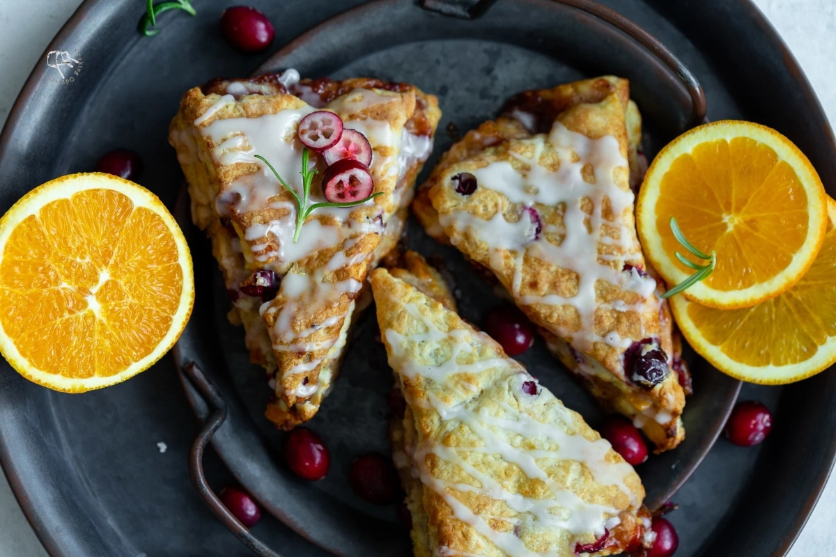 Holiday cranberry orange scones on a plate with orange slices.