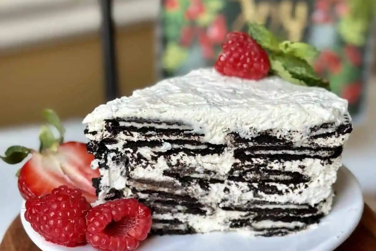 A decadent Oreo cake recipe topped with fluffy whipped cream and adorned with fresh raspberries, perfect for the Christmas season.