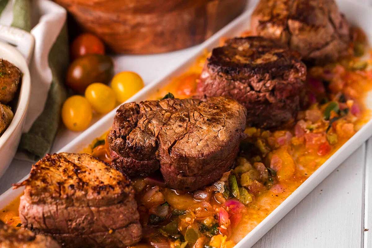 Beef tenderloin with tomato sauce served on a white plate, perfect for a romantic date night.