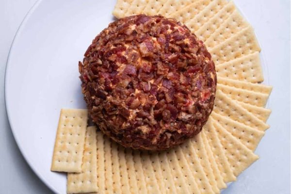 Cheese ball recipes featuring a delectable bacon twist, served alongside crispy crackers on a plate.