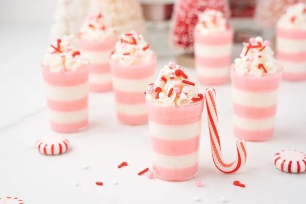 A group of pink and white cups with candy canes in them.