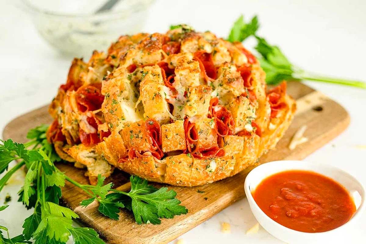 A pizza bread on a cutting board with tomato sauce and parmesan cheese.
