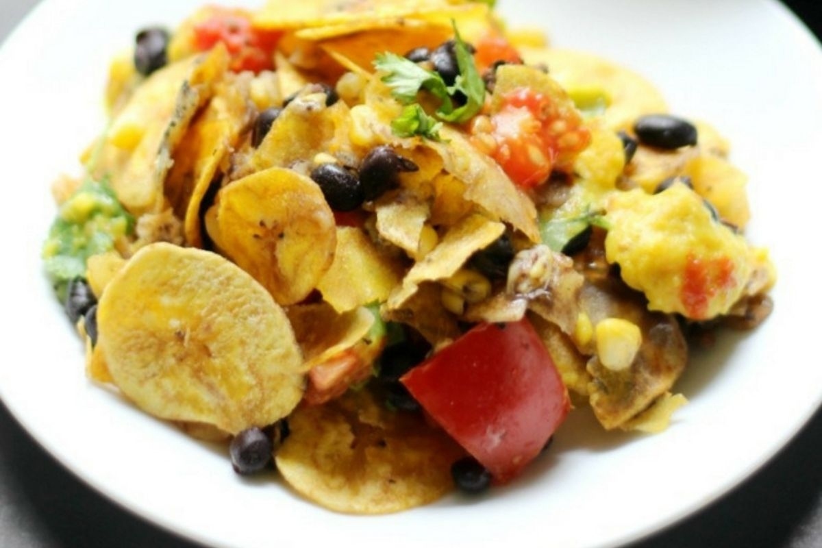 A plate of nachos with black beans and tomatoes.