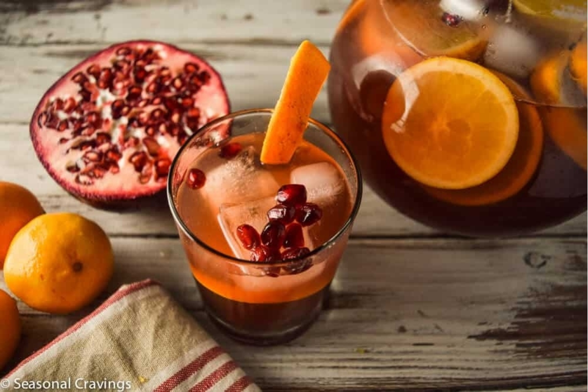 A Thanksgiving cocktail - a glass of pomegranate sangria garnished with orange slices.
