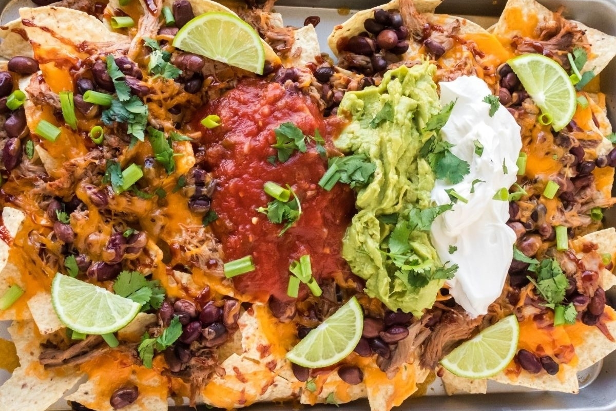 A tray of nachos with guacamole and sour cream.