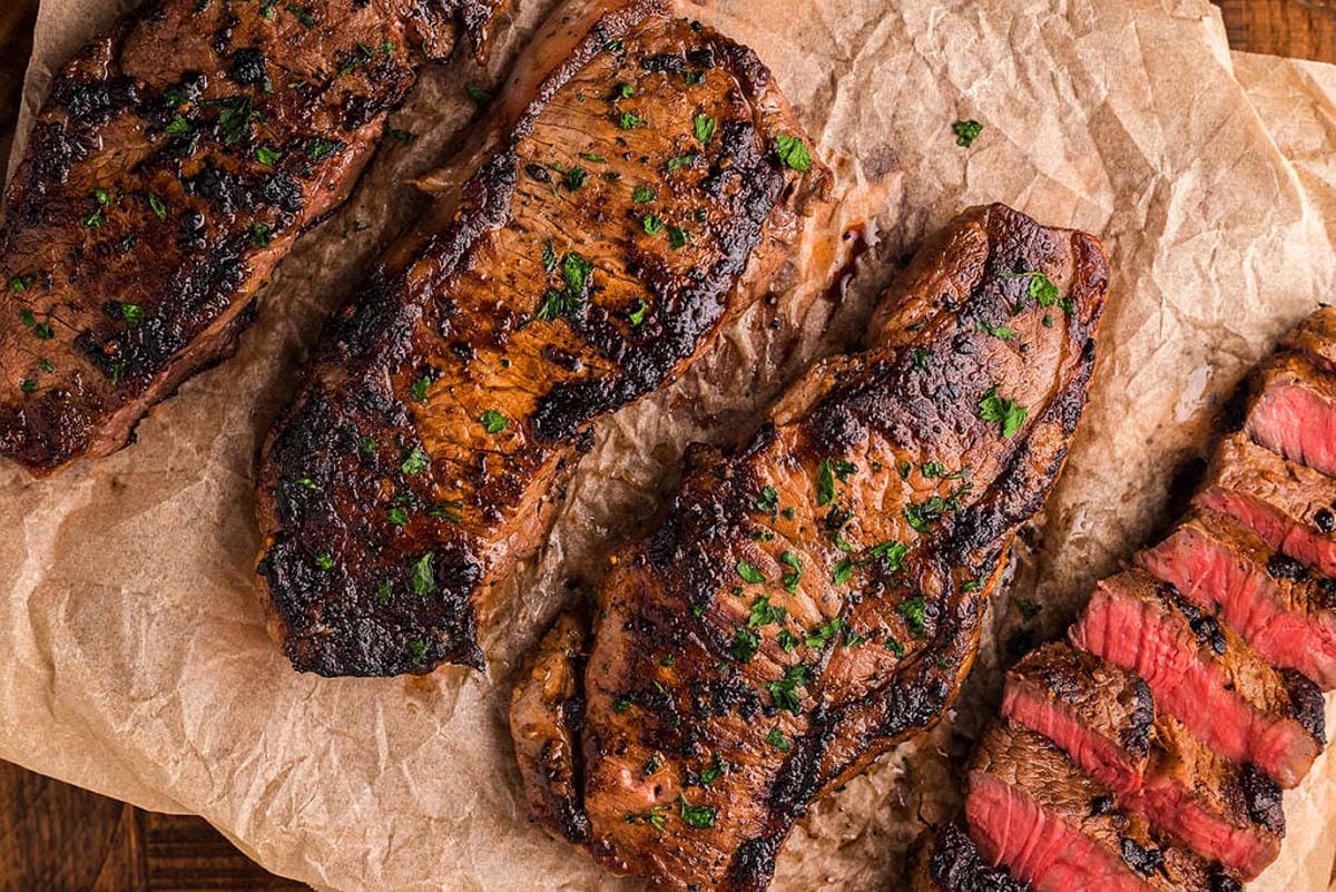 Three pieces of grilled steak on a piece of paper.