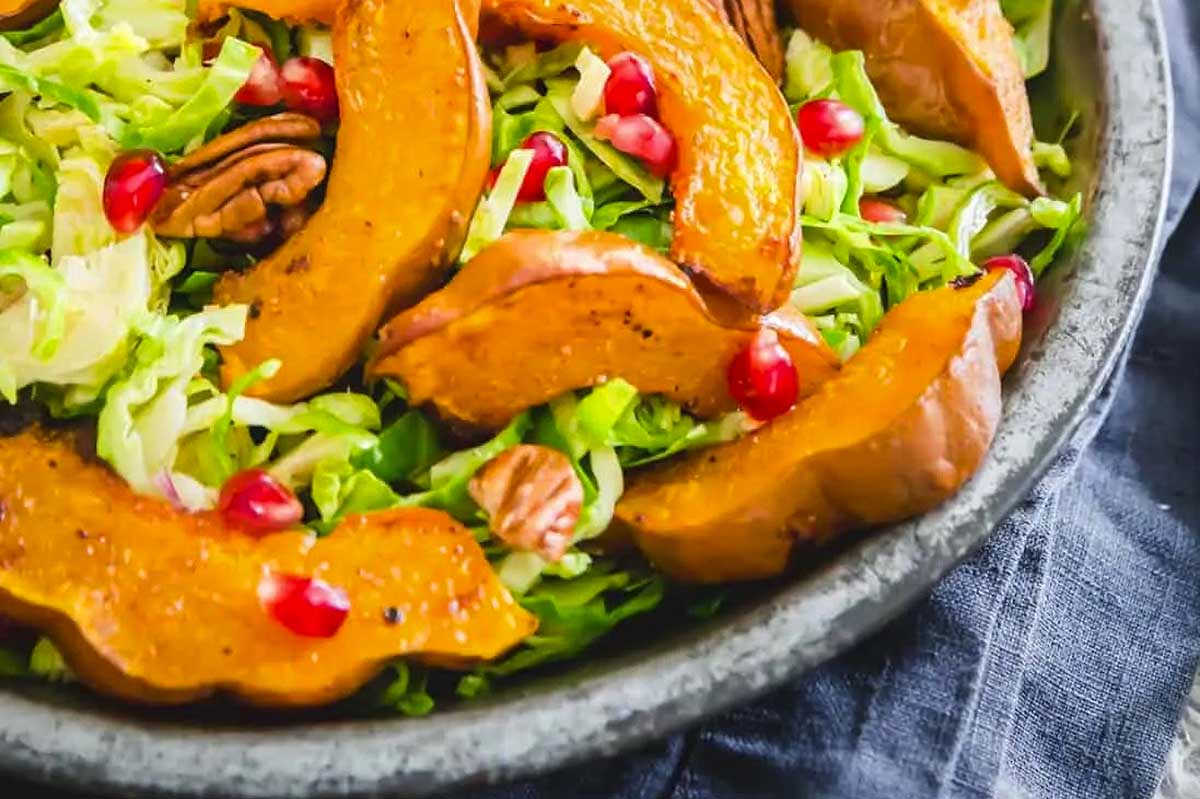 A bowl of roasted squash salad with pomegranate and pomegranate seeds.