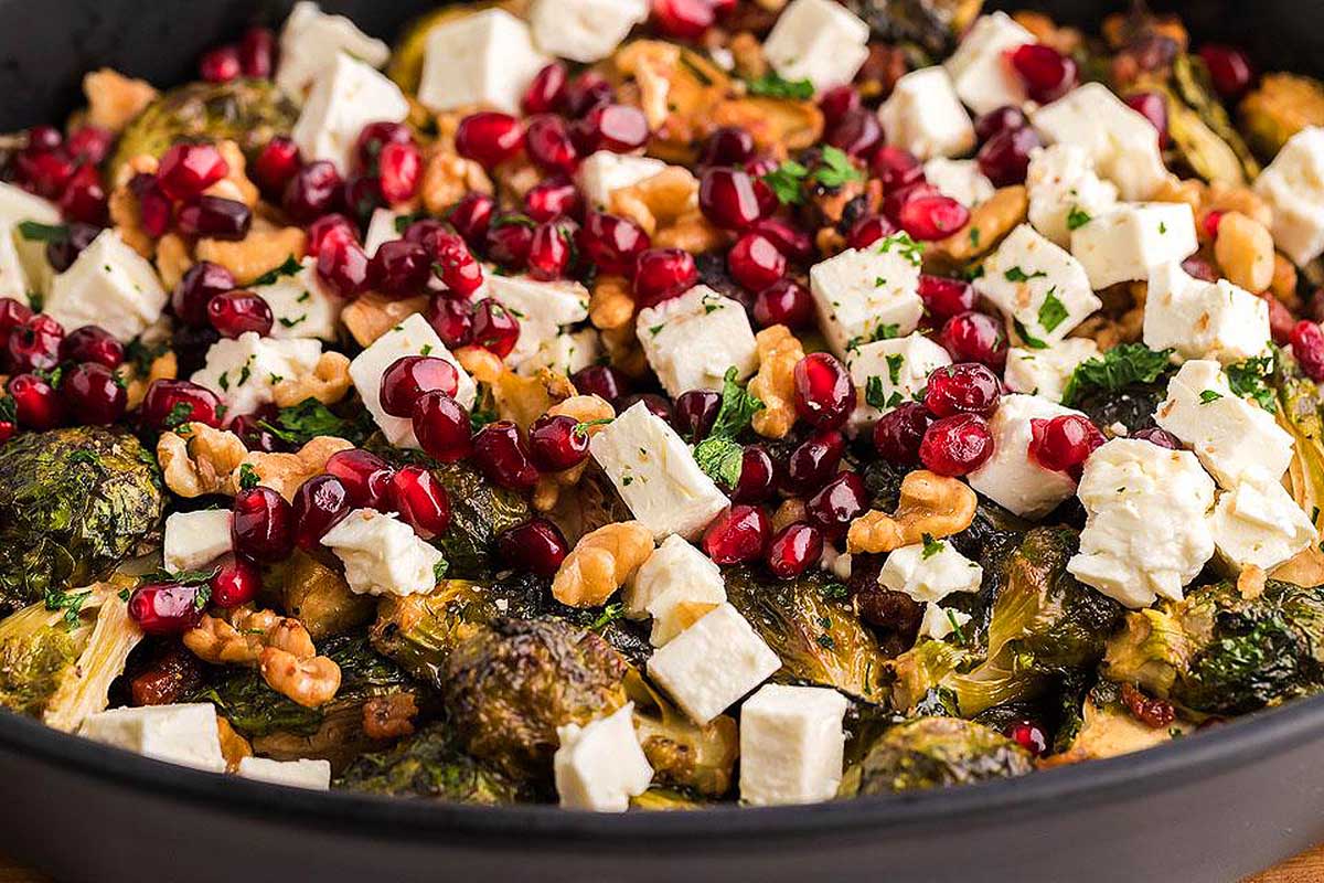 Roasted brussel sprouts with pomegranate and feta in a skillet.