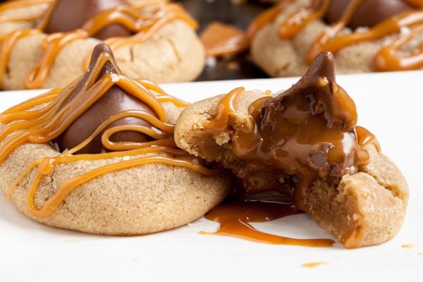 A plate of cookies with caramel sauce and a bite taken out of it.
