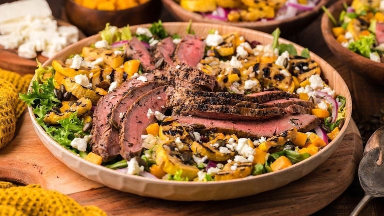 A bowl of steak salad with mango and feta.