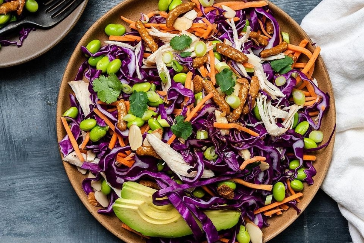 A bowl of red cabbage slaw with carrots and avocado.