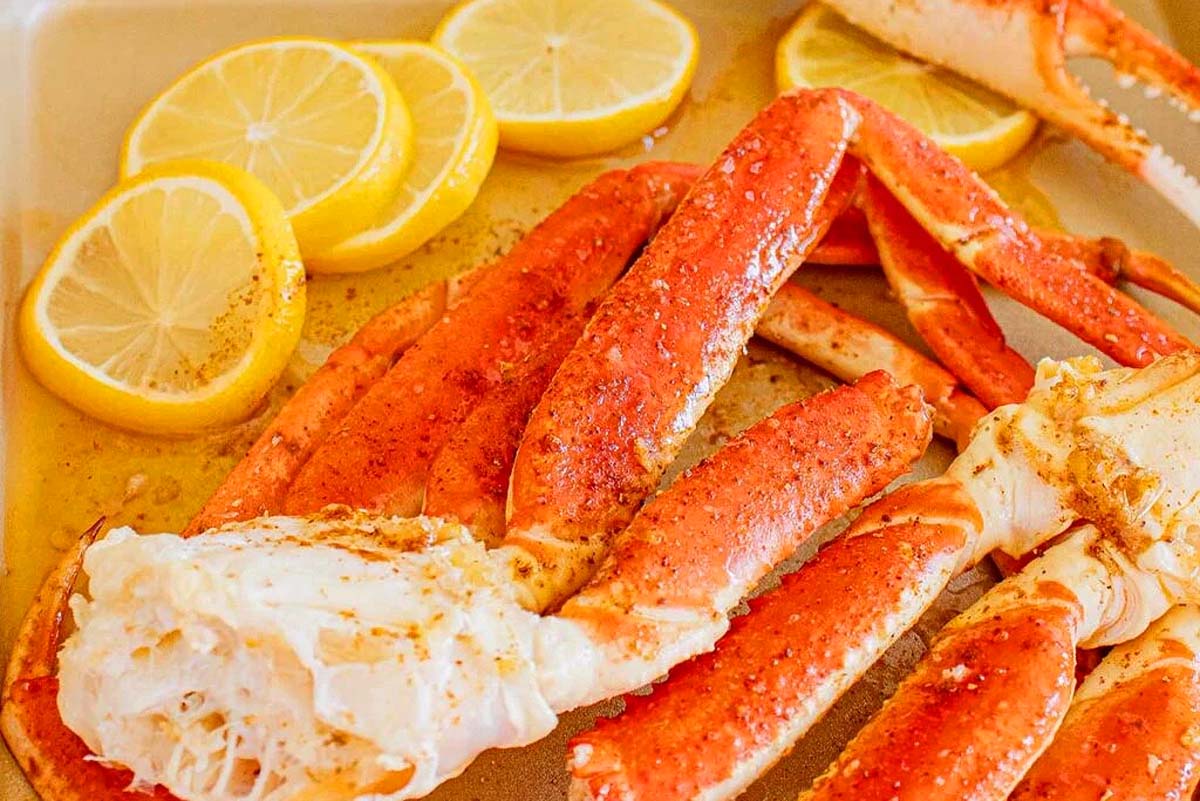 Crab legs on a baking sheet with lemon slices, perfect for a seafood Thanksgiving feast.