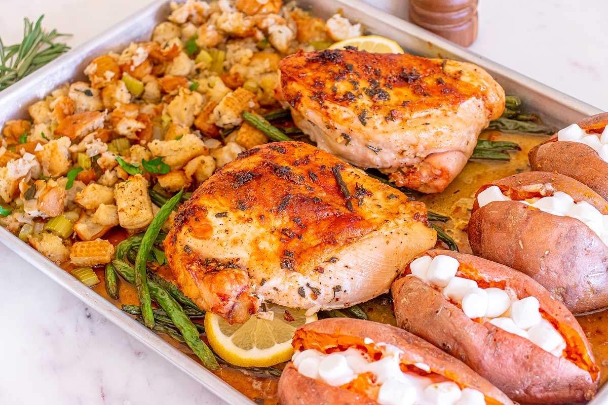Winter comfort dinners with roasted chicken, sweet potatoes, and stuffing on a baking sheet.